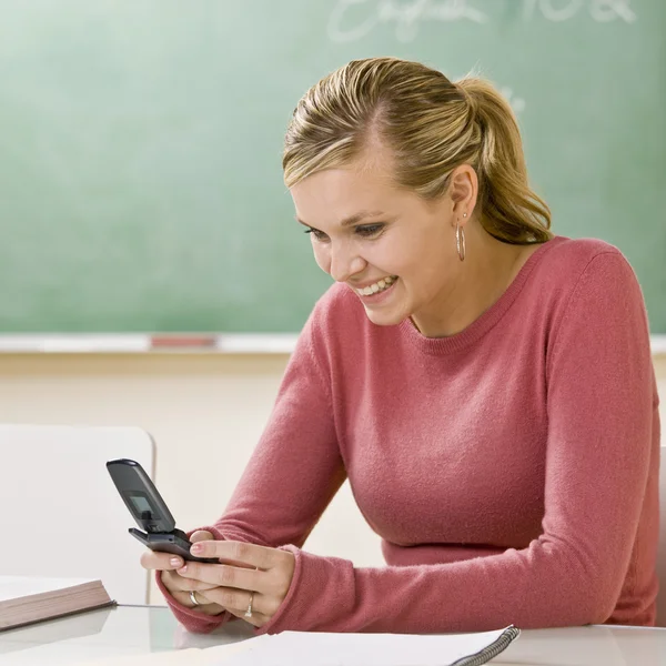 Student text messaging on cell phone in classroom — Stock Photo, Image