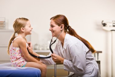 Doctor giving girl checkup in doctor office clipart