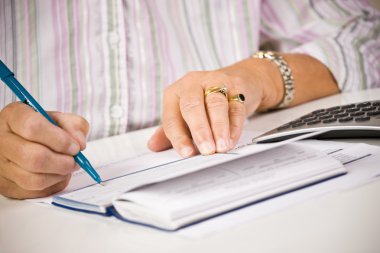 Senior woman writing checks clipart