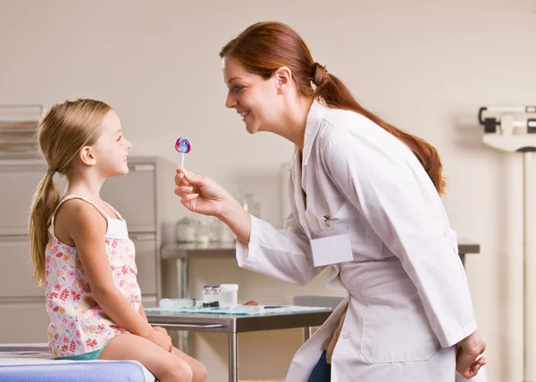 Medico dando ragazza lecca-lecca in ufficio medico — Foto Stock
