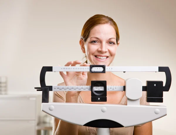 女性医師のオフィスで彼女自身の重量を量る — ストック写真