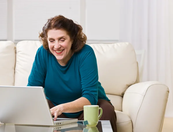 Senior vrouw met laptop in de woonkamer — Stockfoto