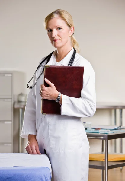 Doutor em consultório médico segurando notebook — Fotografia de Stock