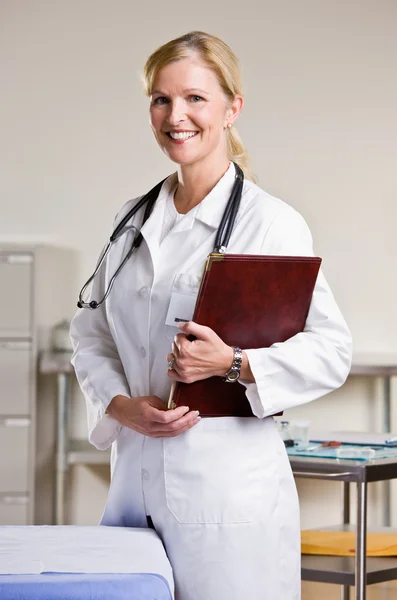 Médico en el consultorio del médico sosteniendo portátil — Foto de Stock