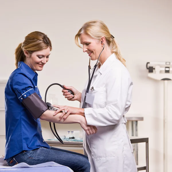 Médico verificando a pressão arterial da mulher — Fotografia de Stock