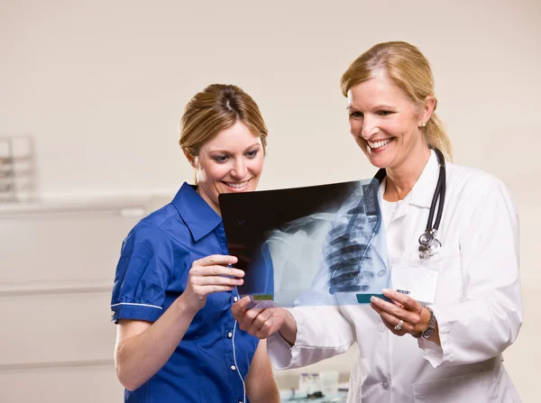 Läkare och kvinna som tittar på röntgen — Stockfoto