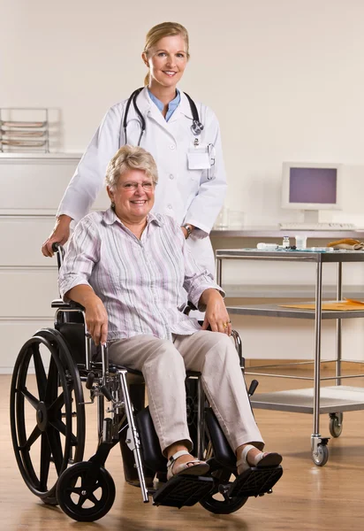 Mujer mayor sentada en silla de ruedas con médico — Foto de Stock