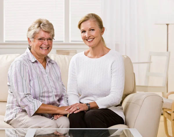 Seniorin sitzt mit Tochter im Wohnzimmer — Stockfoto