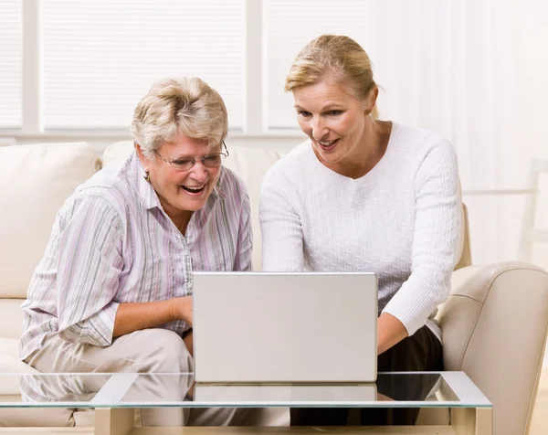 Mujer e hija mayores usando laptop —  Fotos de Stock