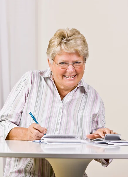 Mujer mayor escribiendo cheques — Foto de Stock