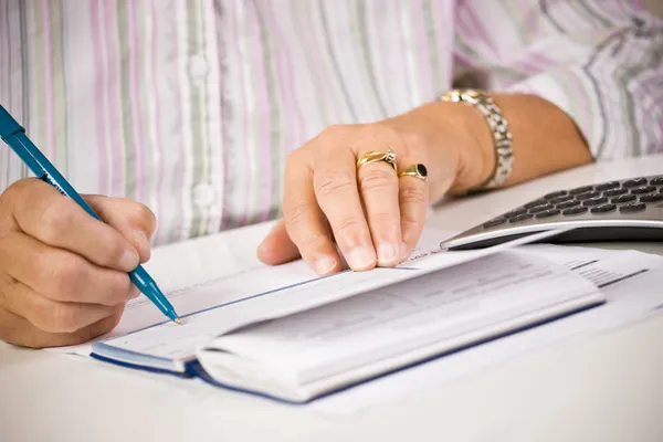 Senior vrouw controles schrijven — Stockfoto