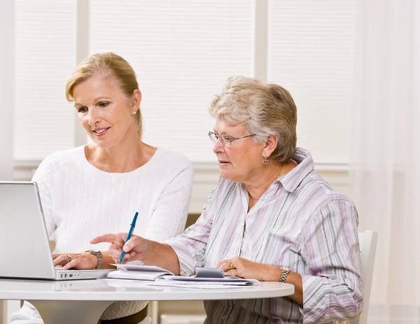 Senior vrouw schrijven controles met dochter hulp — Stockfoto