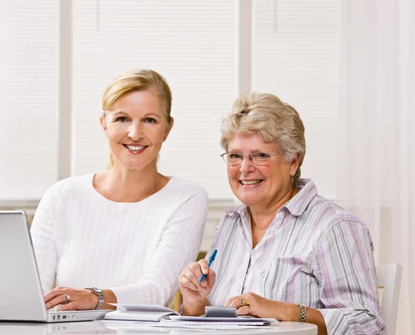 Senior vrouw schrijven controles met dochter hulp — Stockfoto