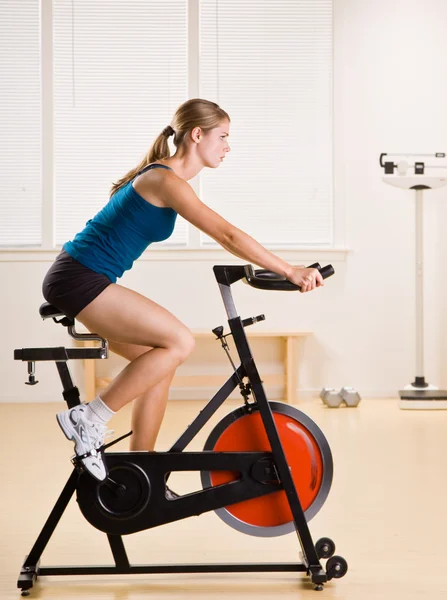 Mujer montando bicicleta estacionaria en el gimnasio — Foto de Stock