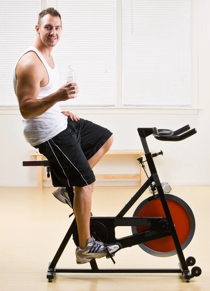 Man riding stationary bicycle in health club — Stock Photo, Image