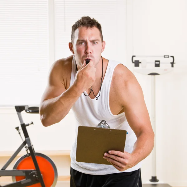 Personal trainer blowing whistle in health club — Stock Photo, Image