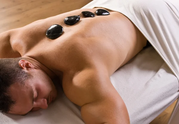 Homem recebendo massagem terapia de pedra quente — Fotografia de Stock