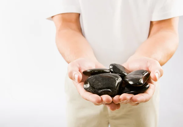 Massage therapist holding warm stones — Stock Photo, Image