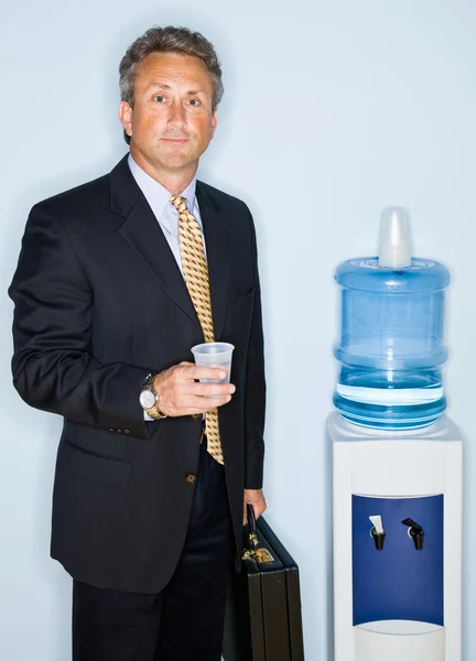Empresário bebendo água do refrigerador de água — Fotografia de Stock