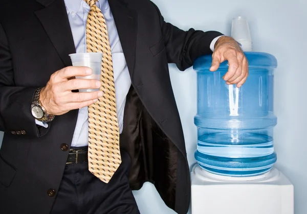 Businessman drinking water from water cooler — Stock Photo, Image