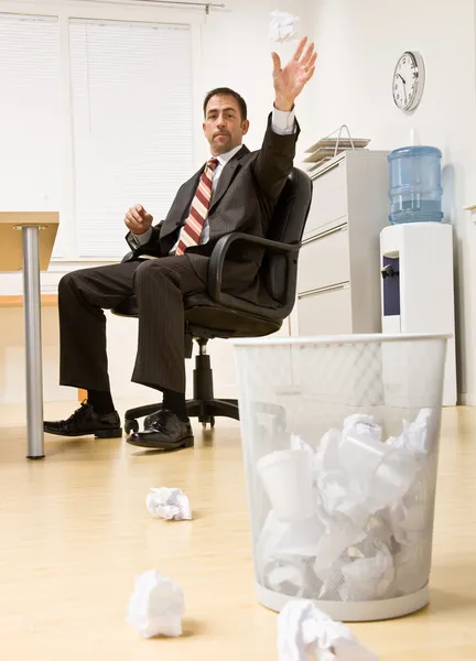 Бизнесмен бросает бумагу в корзину для мусора — стоковое фото
