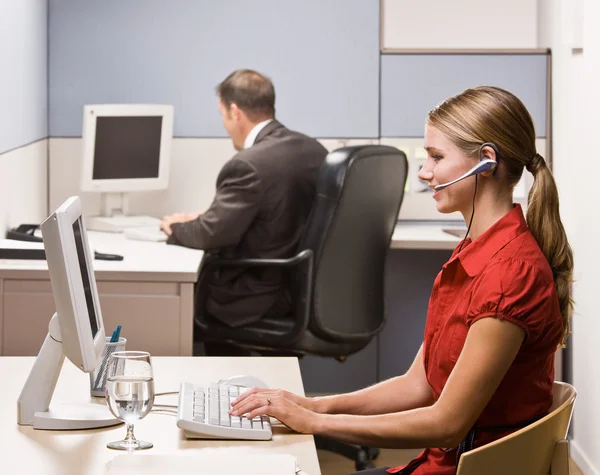 Affärskvinna som pratar på headsetet på skrivbord — Stockfoto