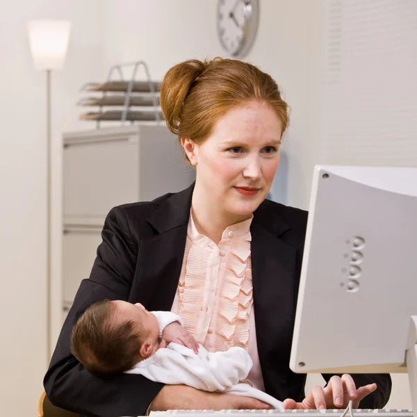 Affärskvinna anläggning baby på skrivbord — Stockfoto