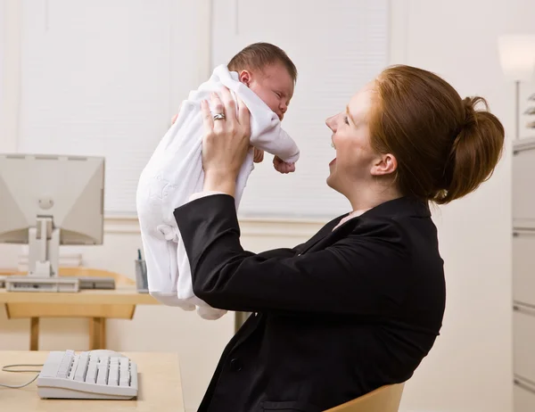 Affärskvinna anläggning baby på skrivbord — Stockfoto