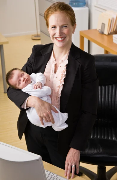 Affärskvinna anläggning baby på skrivbord — Stockfoto