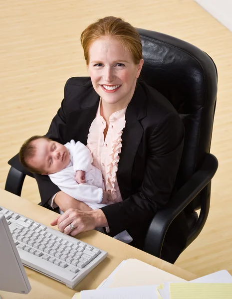 Zakenvrouw bedrijf baby aan balie — Stockfoto