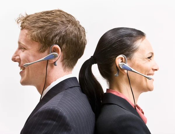 Negocio en auriculares de pie espalda con espalda —  Fotos de Stock