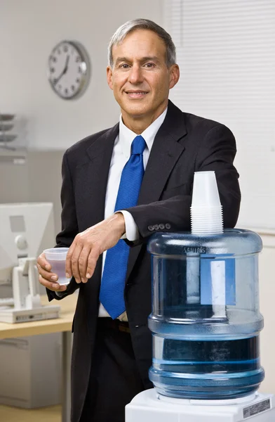Empresário recebendo água do refrigerador de água — Fotografia de Stock