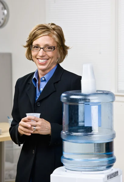 Podnikatelka získávání vody ze chladič vody — Stock fotografie