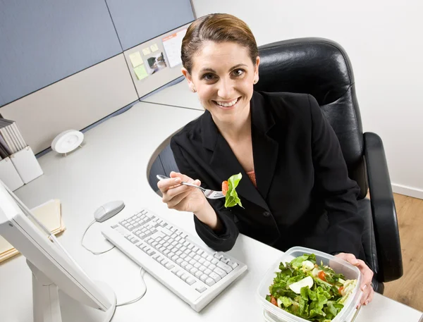 Donna d'affari mangiare insalata alla scrivania — Foto Stock