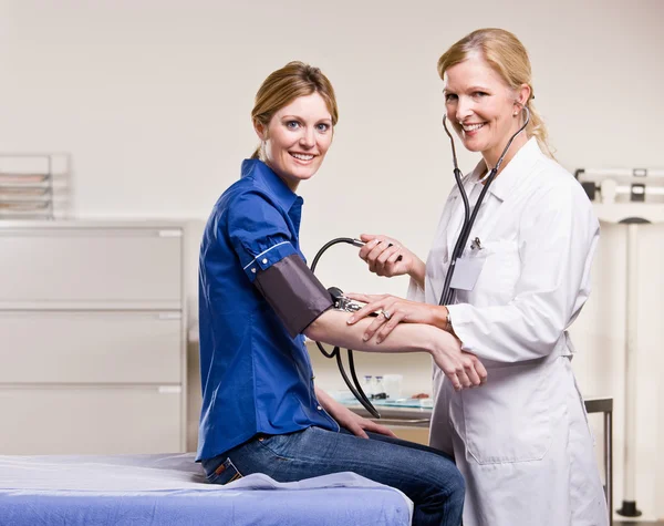 Doctor checking woman blood pressure Stock Picture
