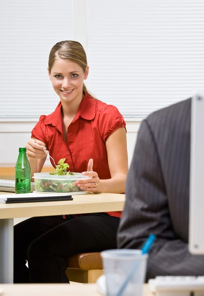 Businesswoman eating salad at desk Stock Image