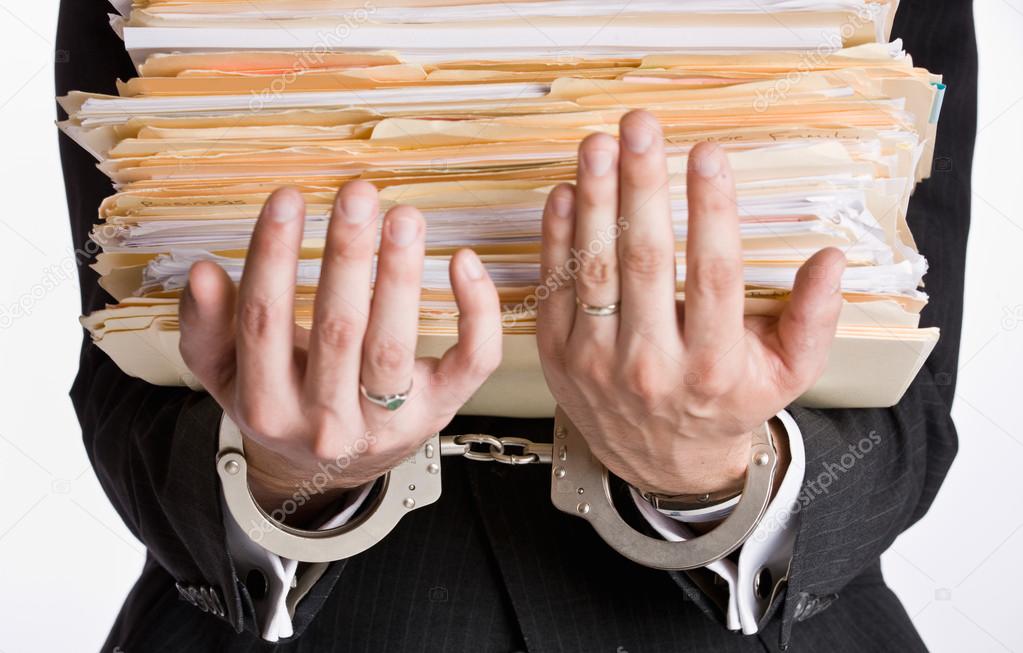 Businessman in handcuffs holding file folders