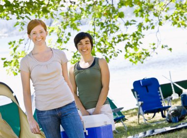 Women carrying cooler at campsite clipart
