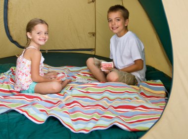 Brother and sister playing cards in tent clipart