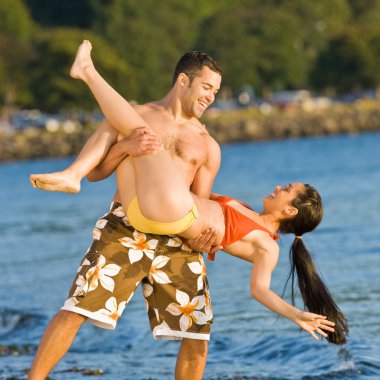 Boyfriend lifting girlfriend on beach clipart