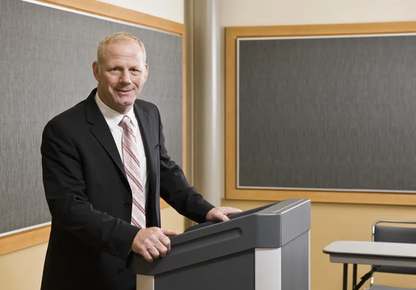 Geschäftsmann steht lächelnd am Podium — Stockfoto