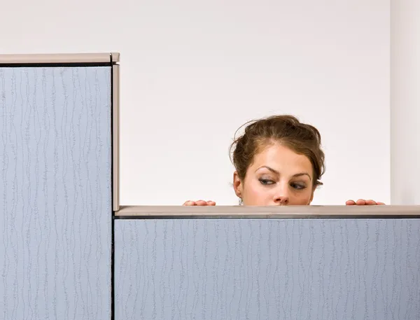 Businesswoman peering over cubicle wall — Stock Photo, Image