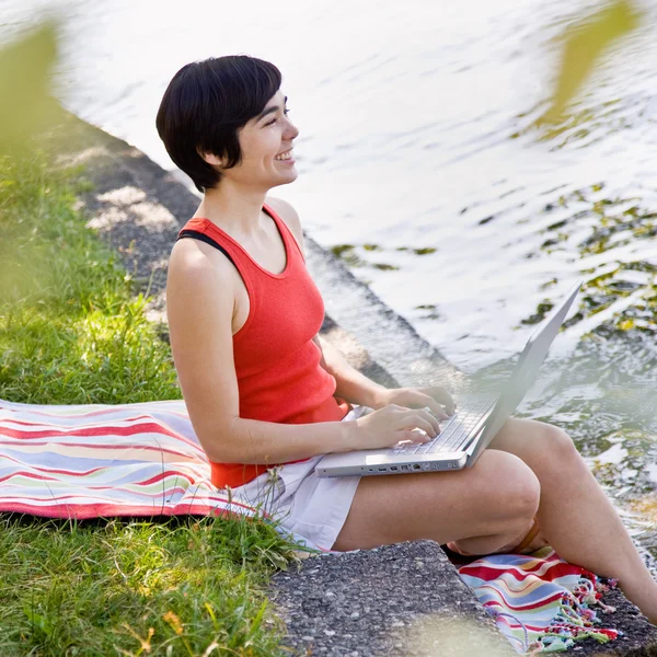 Woman using laptop near pond — Stock Photo, Image