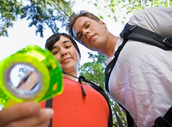 Couple with backpacks looking at compass — Stock Photo, Image