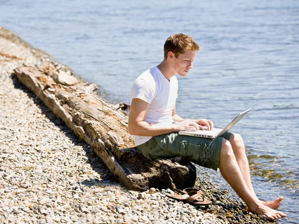 Человек, использующий ноутбук вблизи потока — стоковое фото