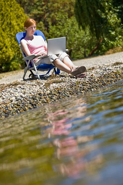 Kobieta korzysta z laptopa w pobliżu strumienia — Zdjęcie stockowe