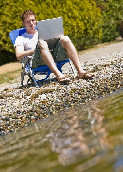 Άνθρωπος χρησιμοποιώντας φορητό υπολογιστή κοντά σε ρέμα — Φωτογραφία Αρχείου