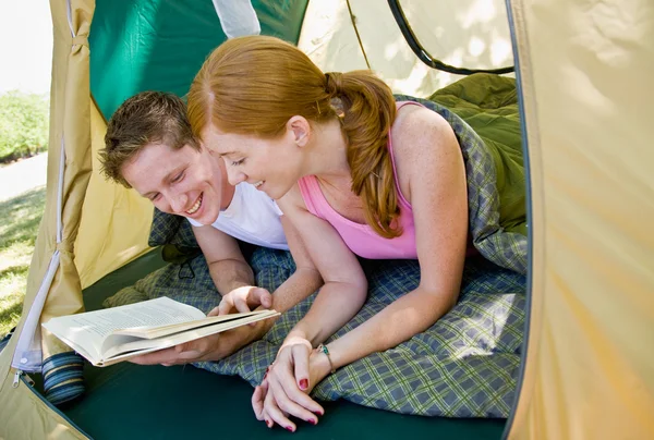 Couple laying in tent reading book — Stock Photo, Image