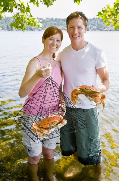 Casal segurando caranguejo e armadilha — Fotografia de Stock