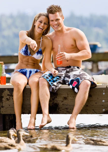 Casal sentado no cais bebendo refrigerante — Fotografia de Stock